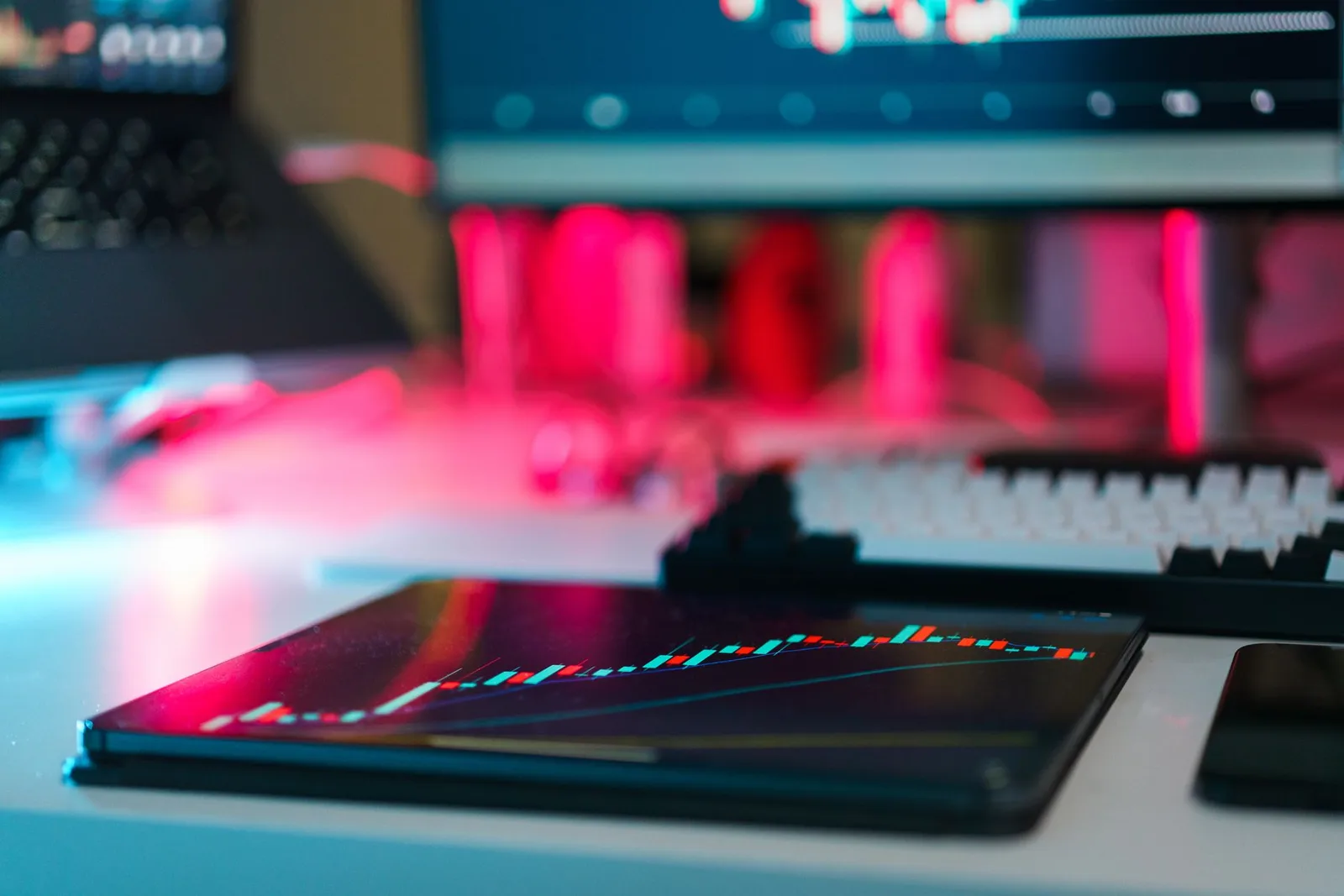 High-tech trading setup with charts on tablet and computer screens, representing data analysis and financial trends.