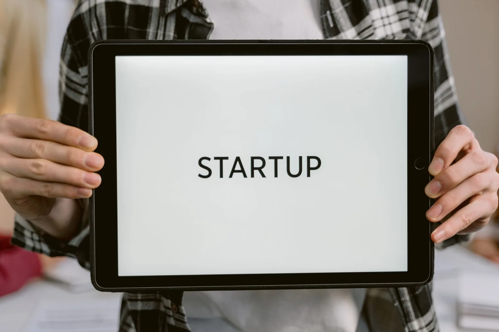 Person holding a digital tablet displaying the word 'STARTUP', representing new business concepts.